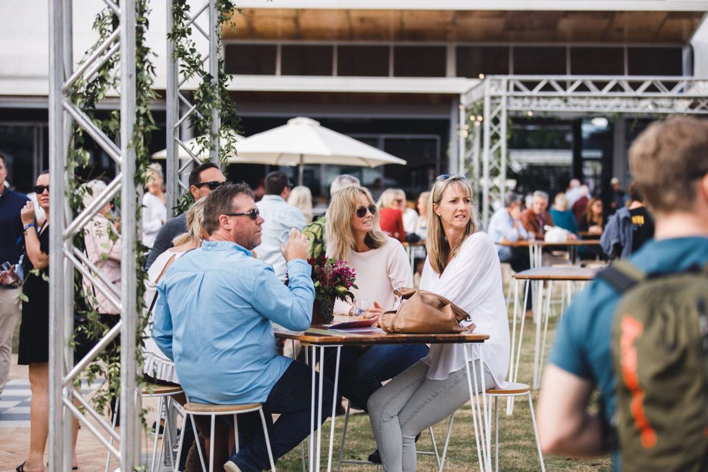 People sitting at tables outdoors during a social event or gathering.