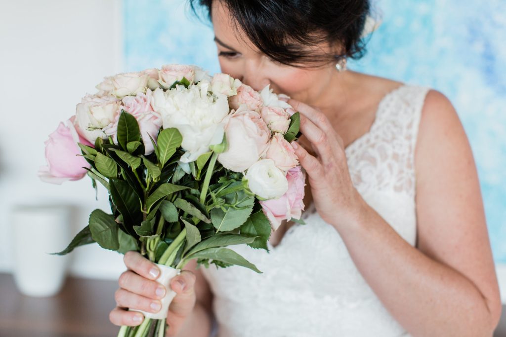 A romantic and elegant bridal bouquet showcasing a soft color palette of pink and white. The bouquet features a mix of lush peonies, delicate ranunculus, and romantic roses, creating a textural and captivating arrangement